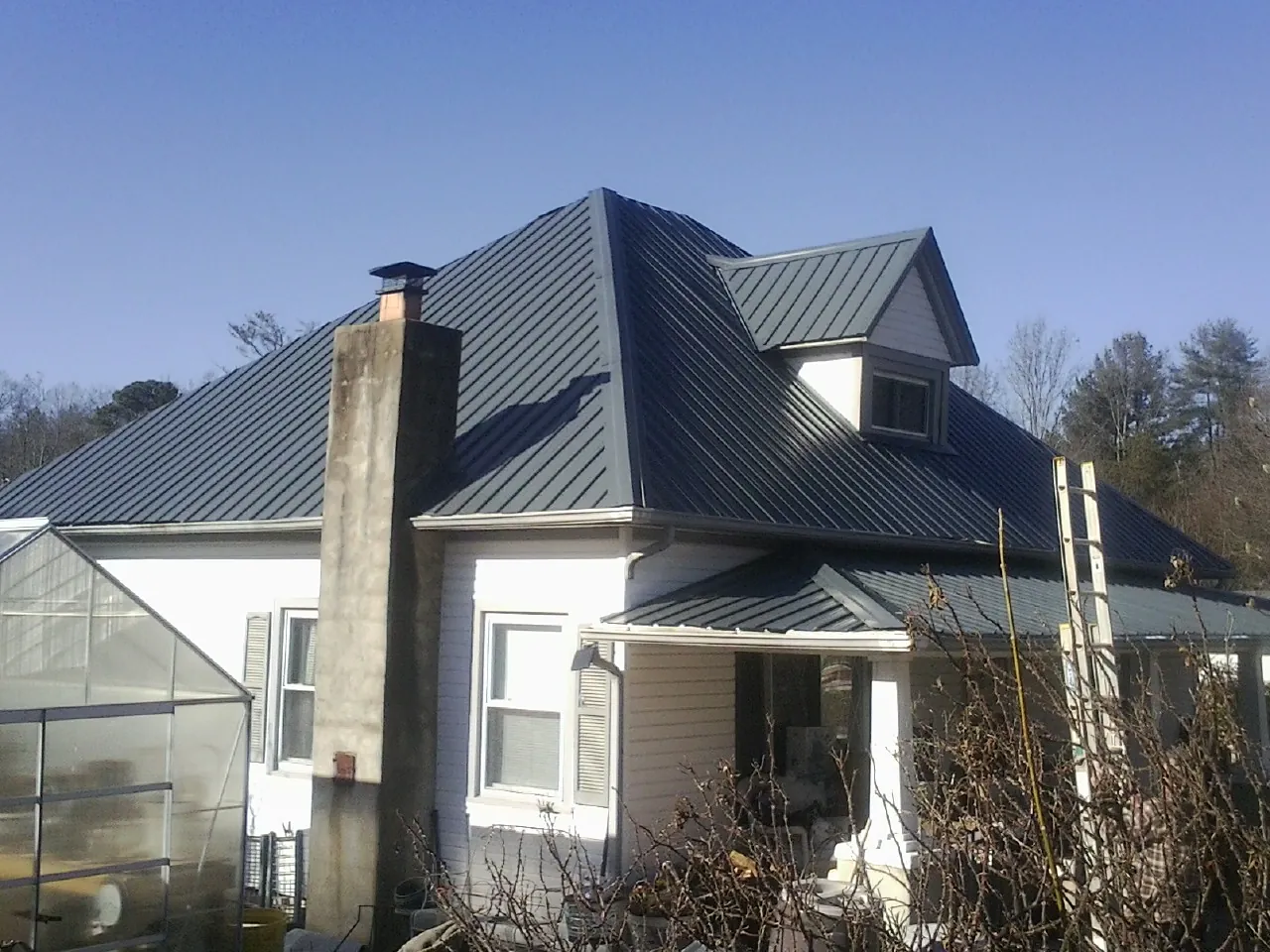Dark blue standing seam metal roof on a white farmhouse with dormer — Slate & Tile Roof Repair by Roofing Brothers in Knox