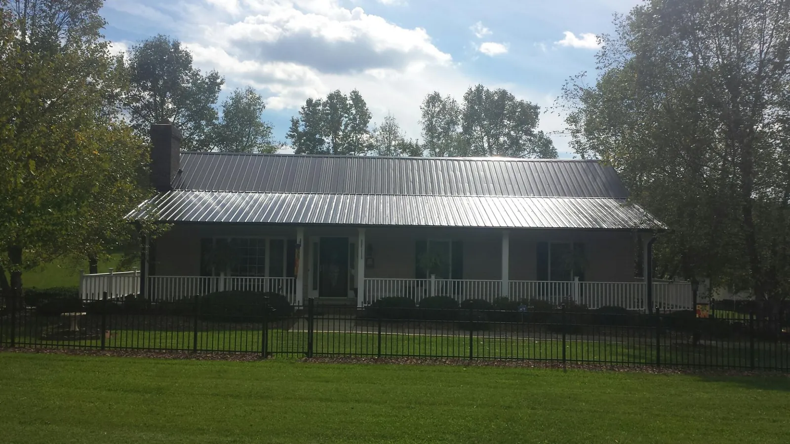 Gray metal roof on a brick ranch with a full width front porch — Gutter Guard Installation work by our crew in Knox