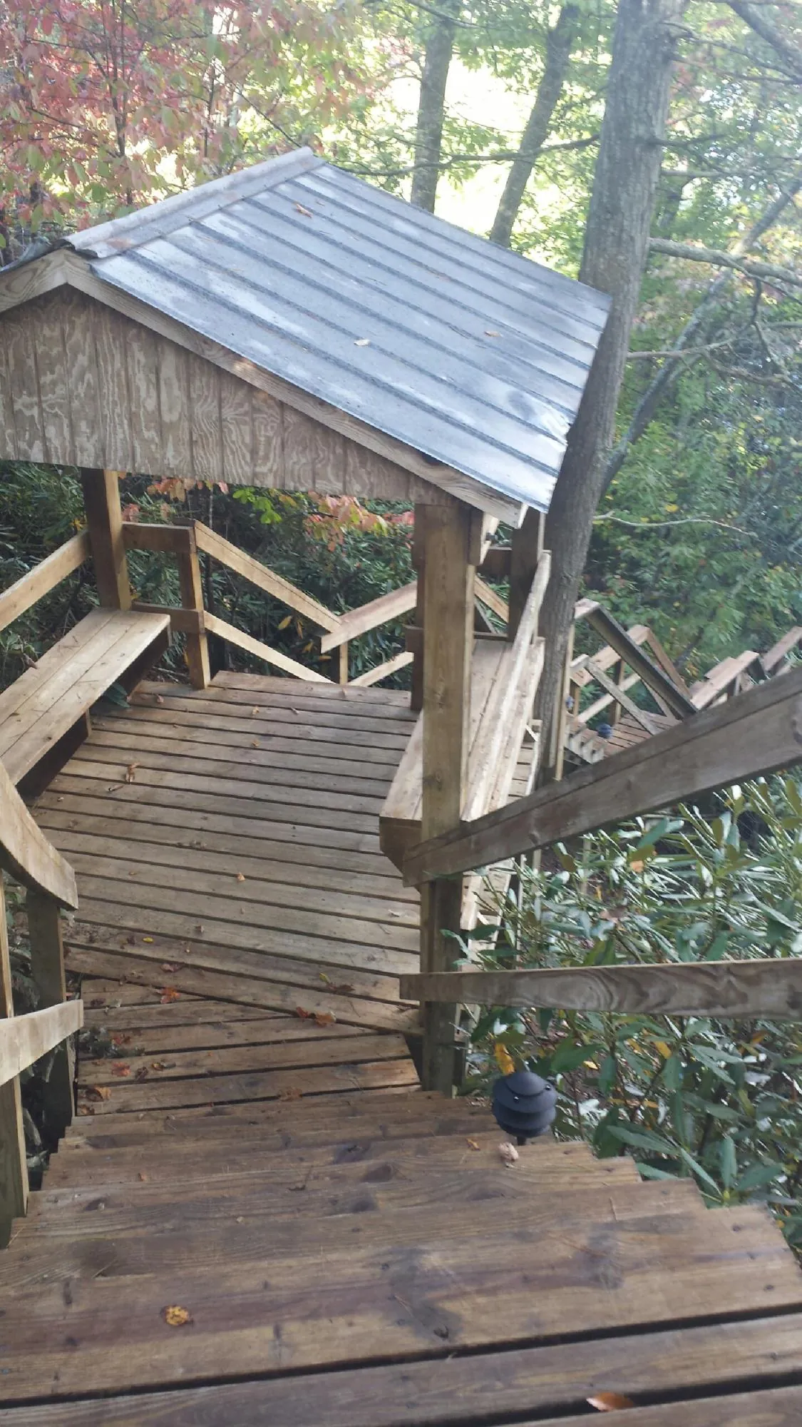 Metal roofed shelter over wooden steps on a wooded walkway — Skylight Repair & Installation work by our crew in Knox