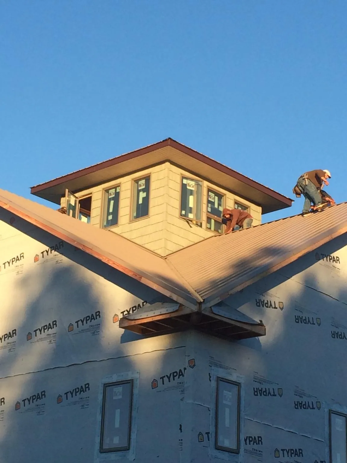 Roofers working around a rooftop cupola on a new metal roof at sunset — Roof Waterproofing in Knox by Roofing Brothers